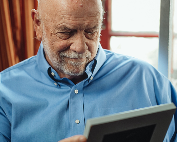 Elderly man looking at photo wearing a blue shirt