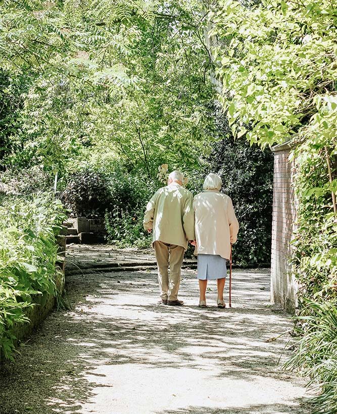 elderly couple walking under trees