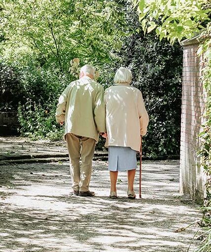 elderly couple walking under trees